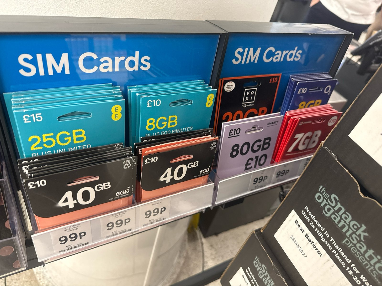 Стойка с предоплаченными SIM в Tesco: EE 25 ГБ за £15, EE 8 ГБ, Three 40 ГБ, Voxi 20 ГБ, Smarty 80 ГБ, o2 8 ГБ, Tesco Mobile 40 ГБ, Vodafone 7 ГБ. Пакет £10, сама SIM 99p