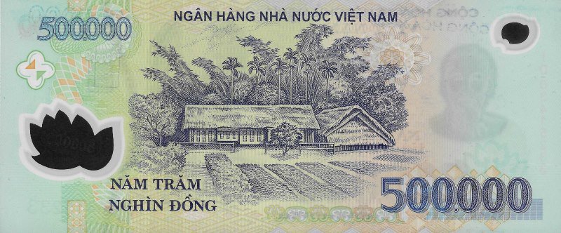 Reverse of the 500,000 đồng Vietnamese polymer banknote: detailed engraving of Hồ Chí Minh's thatched-roof childhood home at Làng Sen, with bamboo-and-timber walls, a low fence, a fruit tree, rice paddies in front and the mountains of Nghệ An behind, on a cyan-blue polymer ground