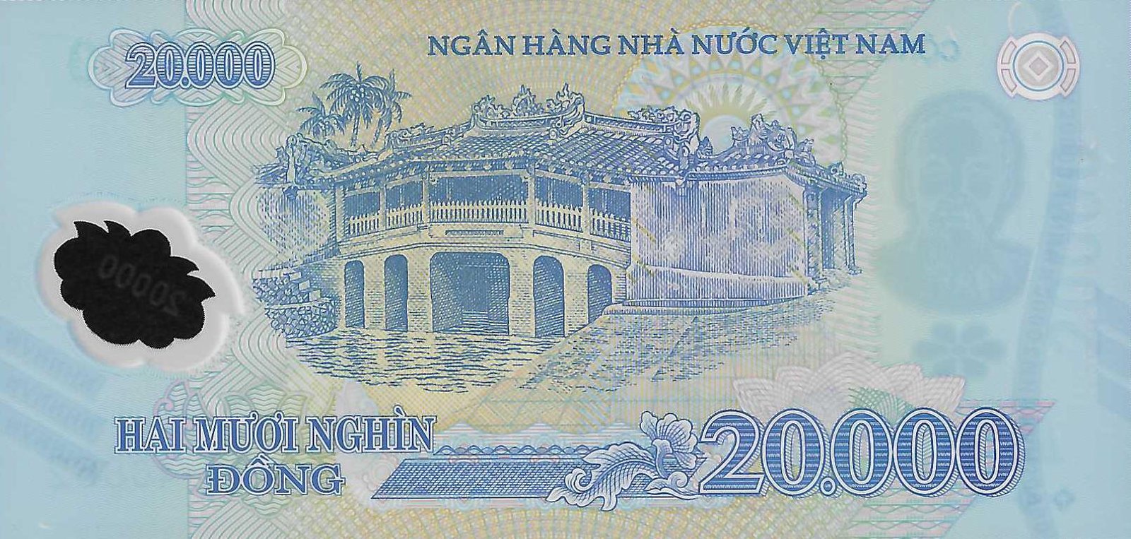 Reverse of the 20,000 đồng Vietnamese polymer banknote: detailed engraving of Chùa Cầu, the wooden Japanese Covered Bridge of Hội An, with its tiled roof, arched spans, the small shrine at the upper level, reflection in the water and palms behind, on a turquoise-blue polymer ground